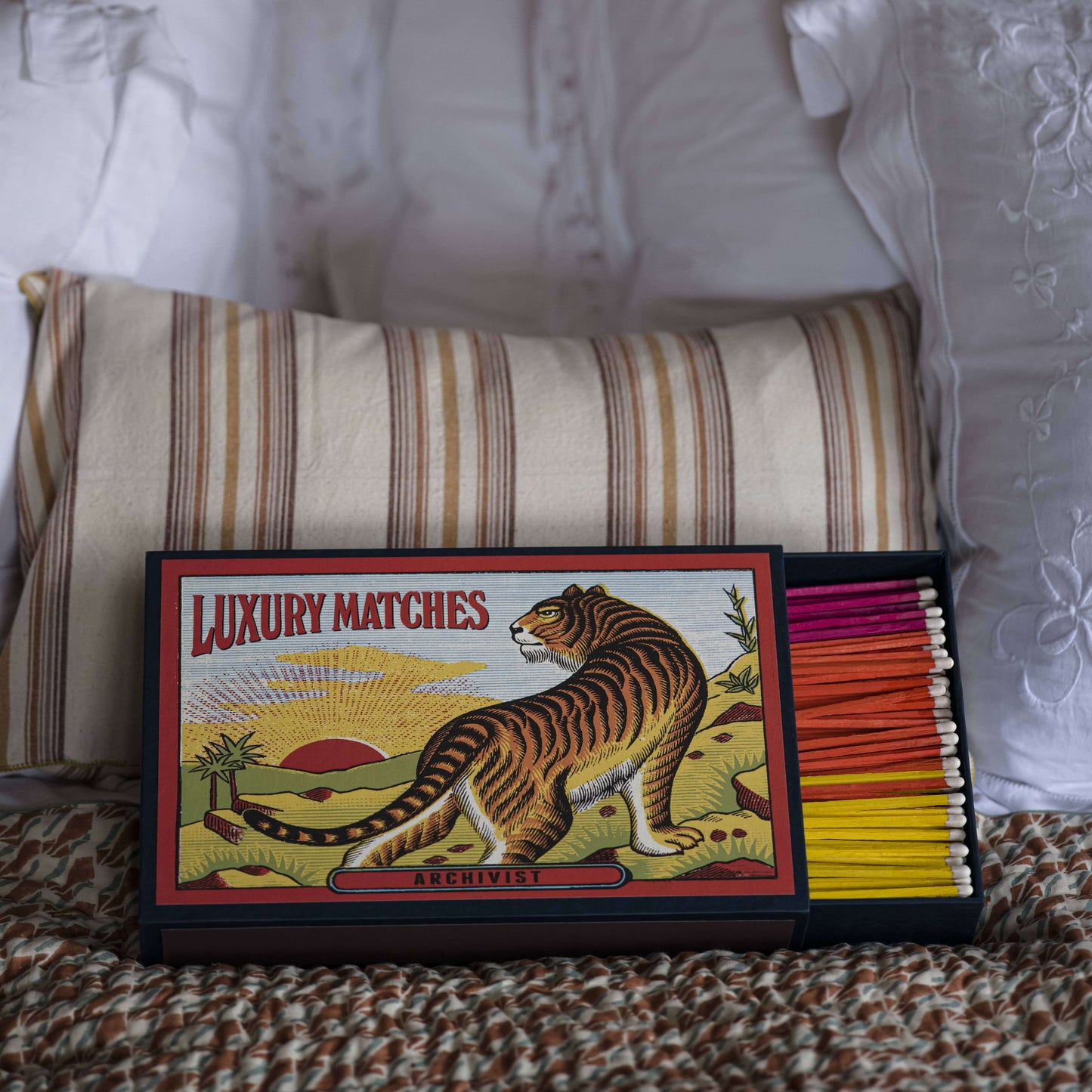 The Tiger | Giant - Safety Matches displayed on a bed with colorful matchsticks and decorative pillows.