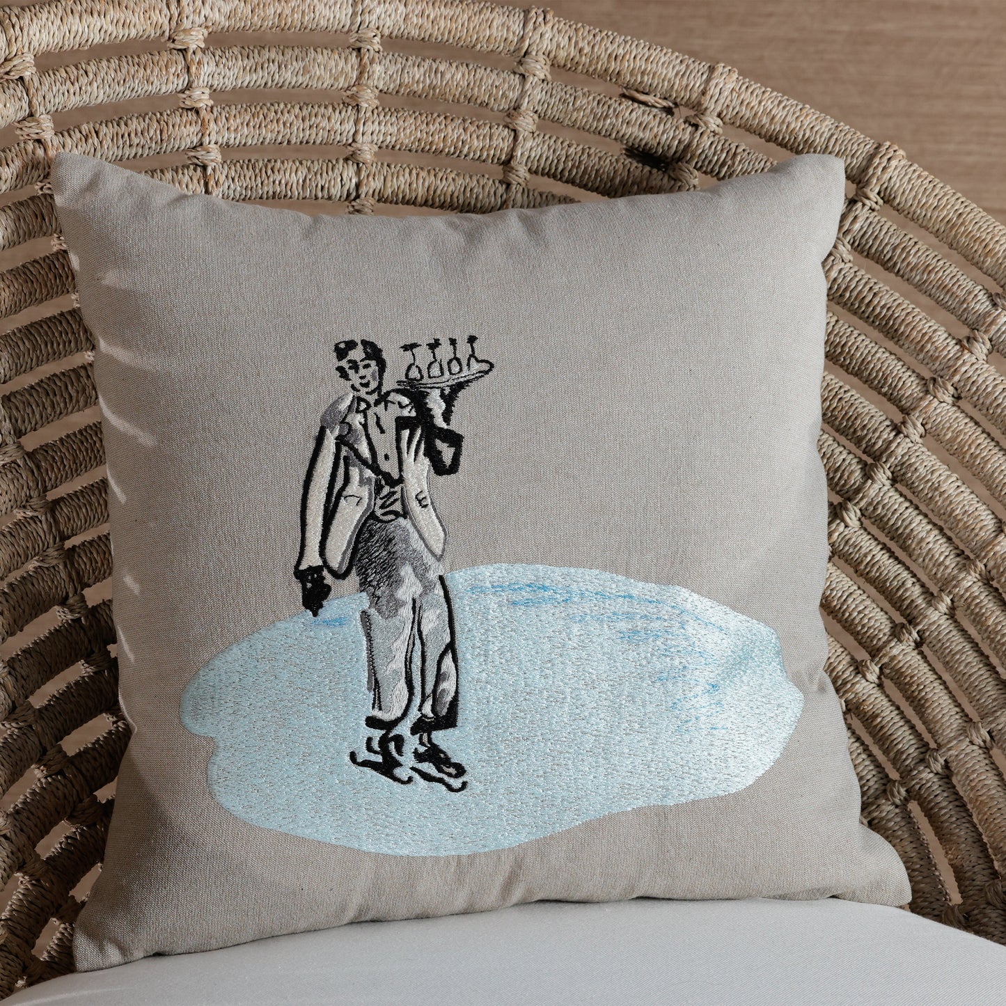 Decorative pillow with a vintage-style illustration of a man in a suit on a wicker chair.