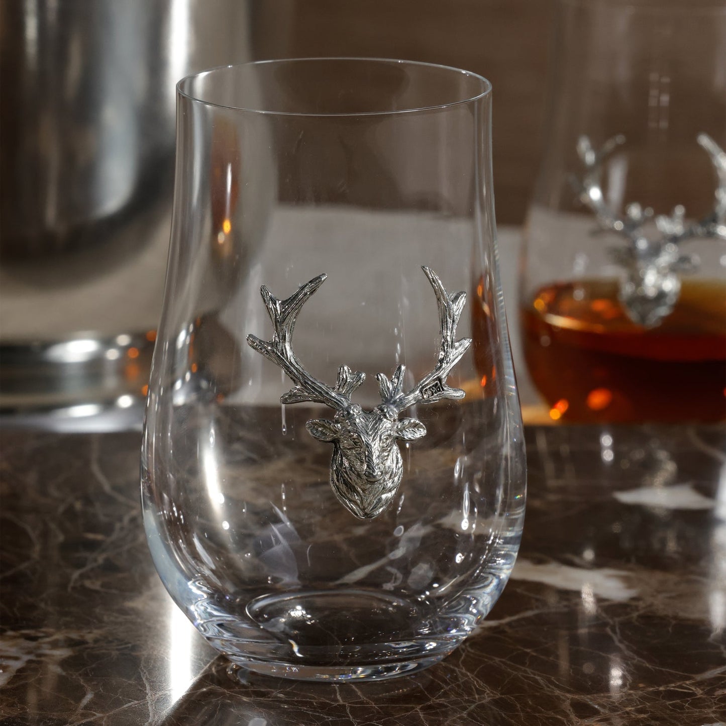 Clear glass with deer head design on a marble surface
