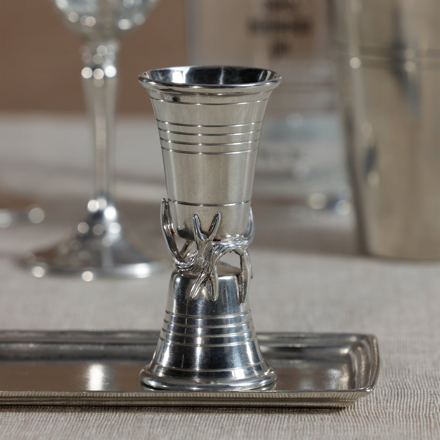 Silver candle holder on a reflective surface with blurred background