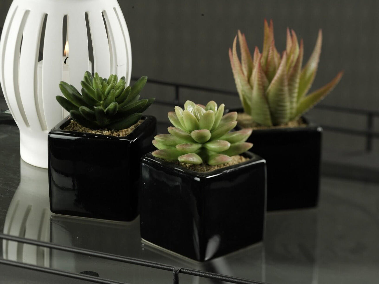 Artificial Flowers in black pots with a white lantern for home decor.