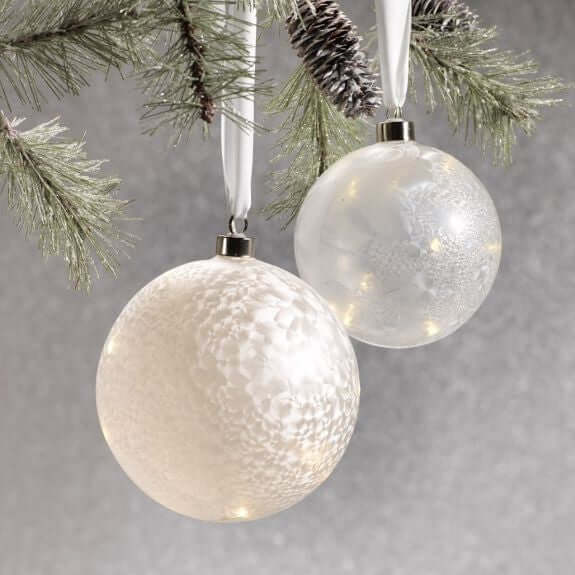 LED Decor & Gifts - elegant white and frosted ornaments hanging from a pine branch for holiday decorations.