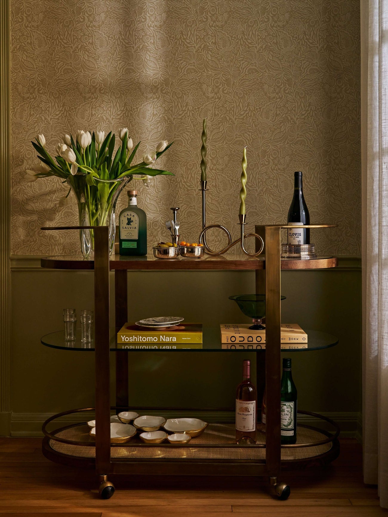Accent Furniture bar cart displaying bottles, glasses, and flowers, enhancing the decor with style and elegance.