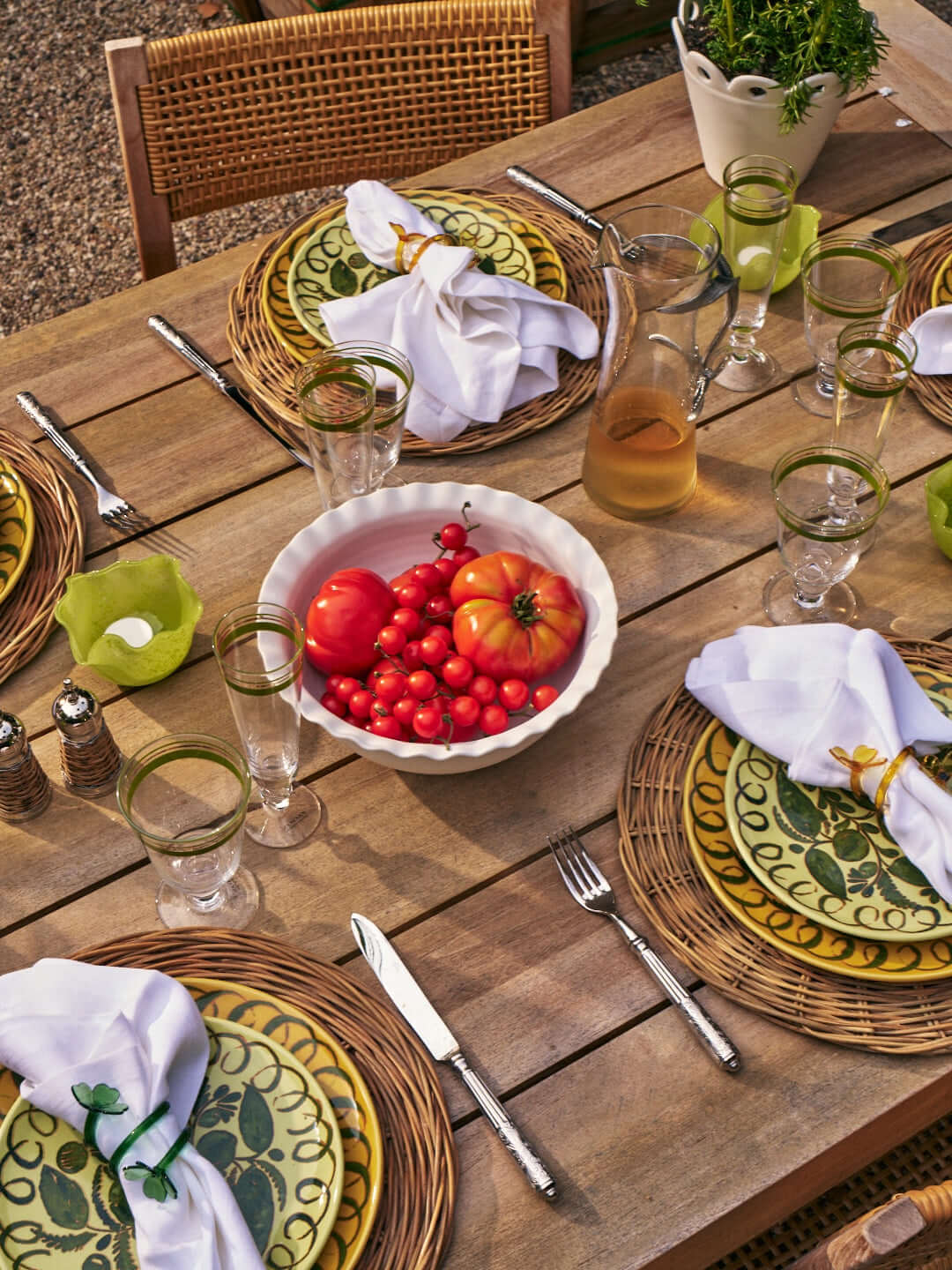 Summer Entertaining Essentials setting with colorful dishes, fresh tomatoes, and elegant glassware on a wooden table.
