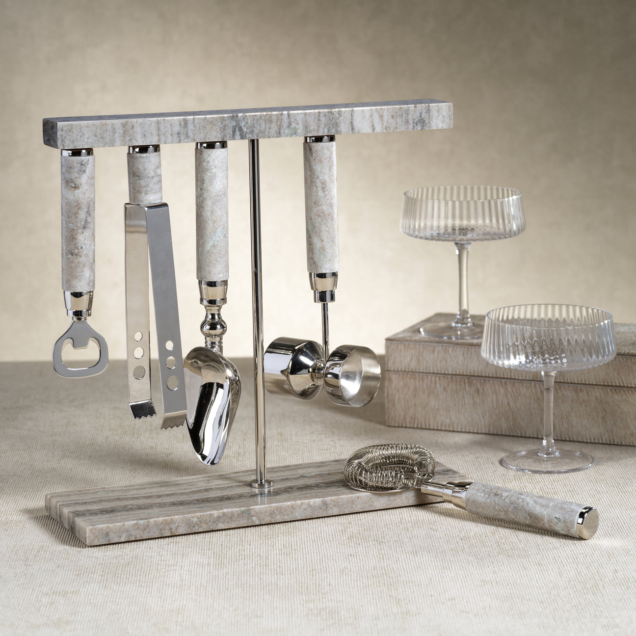 Stylish collection of bar tools including a bottle opener, jigger, and strainer for cocktail enthusiasts.
