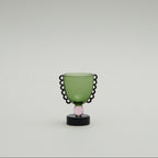 Green glass object with black decorative rim on a white background