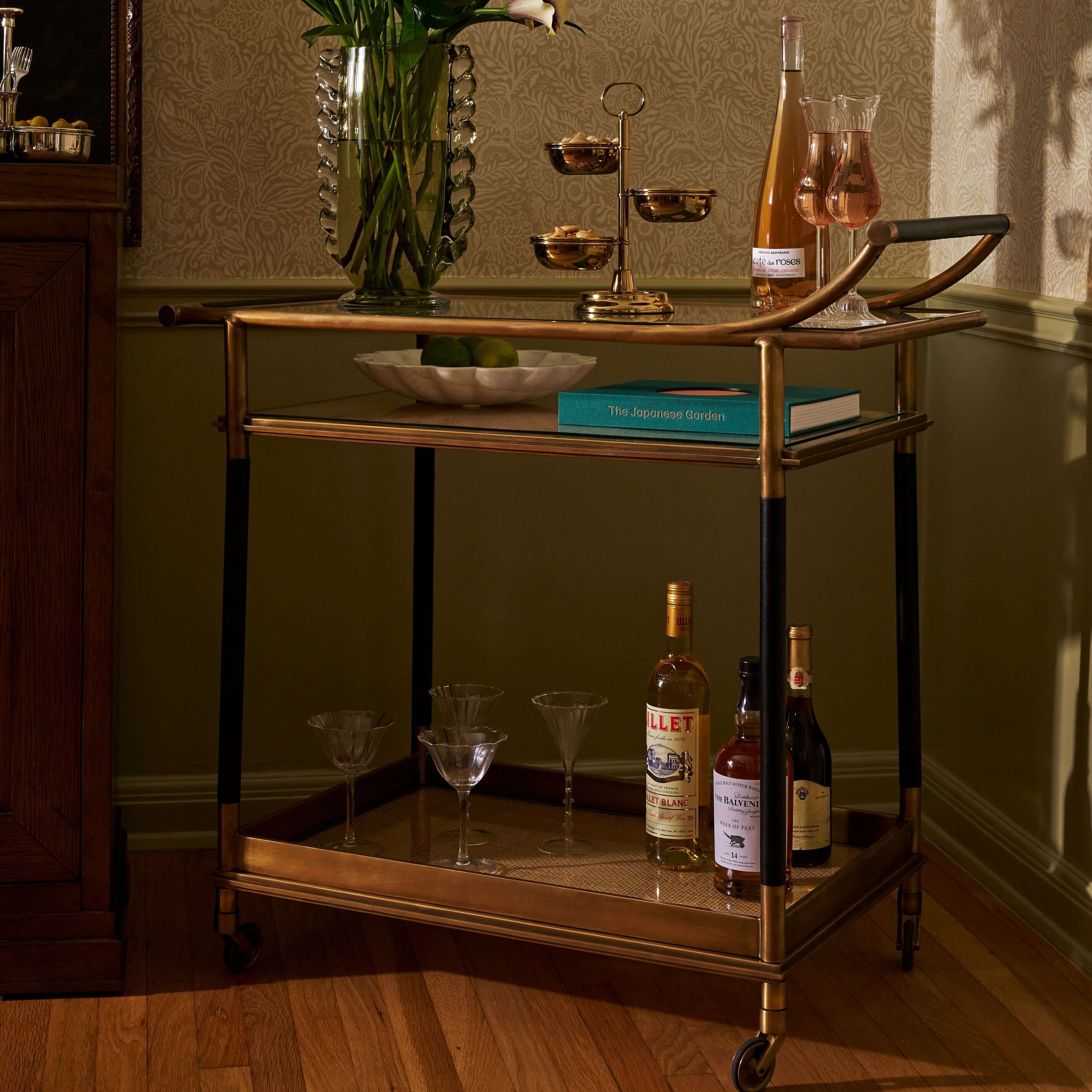 Stylish Mayfair 59 Bar Cart showcasing drinks, elegant glassware, and a decorative bowl on a luxurious antique brass frame.