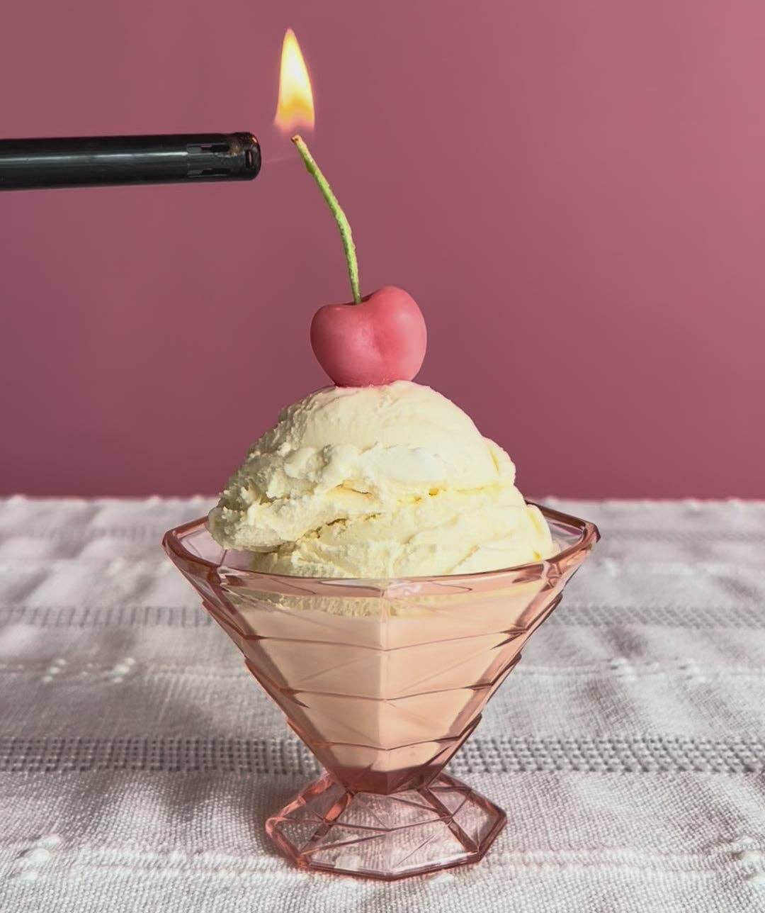 Pink Cherry Birthday Beeswax Candles on top of a dessert with a pink background and a flame