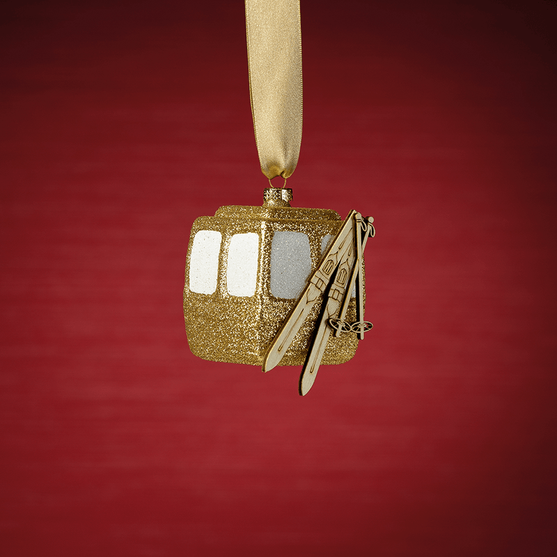 Gold glittery cable car ornament on a red background