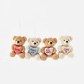 Four teddy bears with heart-shaped messages hanging against a white background