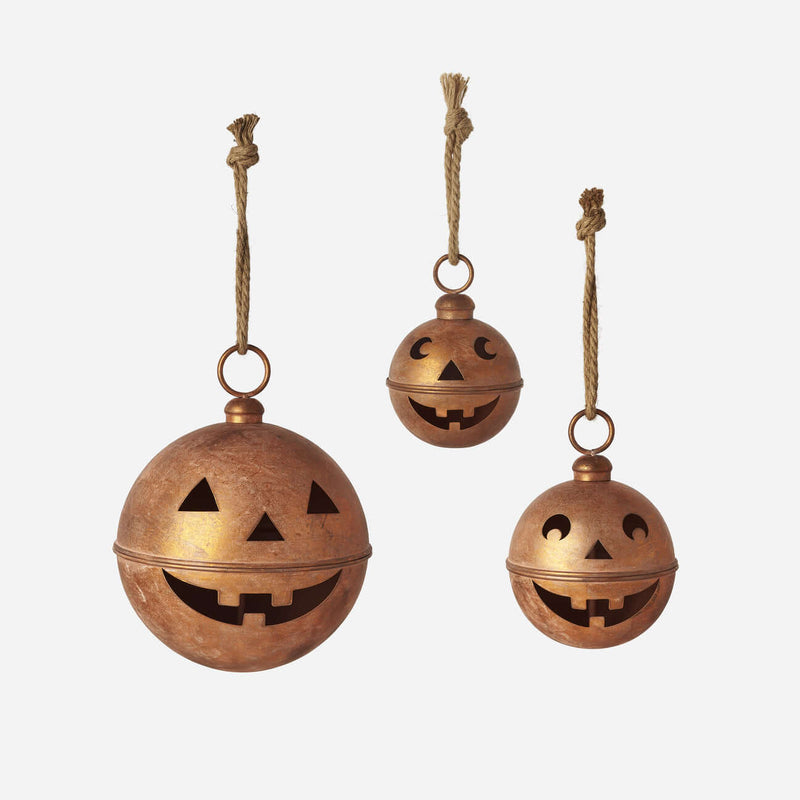 Pumpkin Bell Display featuring small copper metal lanterns with playful jack-o'-lantern cutouts and jute rope hangers.