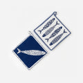 Set of two assorted fish-shaped quilted hot pads for kitchen and table use.
