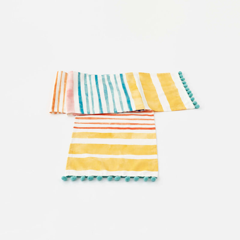 Terrazzo Table Runner with Pompom Trim showcasing vibrant stripes and teal pompom accents.