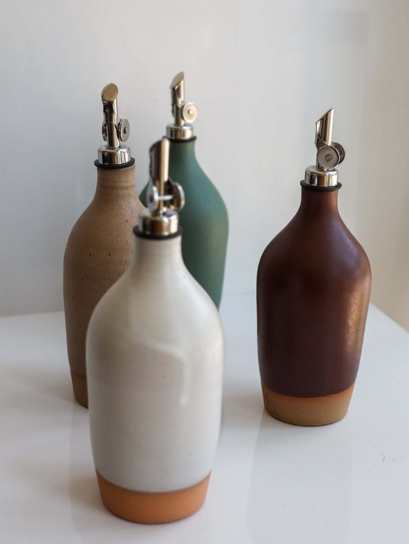 Tall Handmade Ceramic Oil Bottle assortment in matte glaze with polished pourers on a counter.