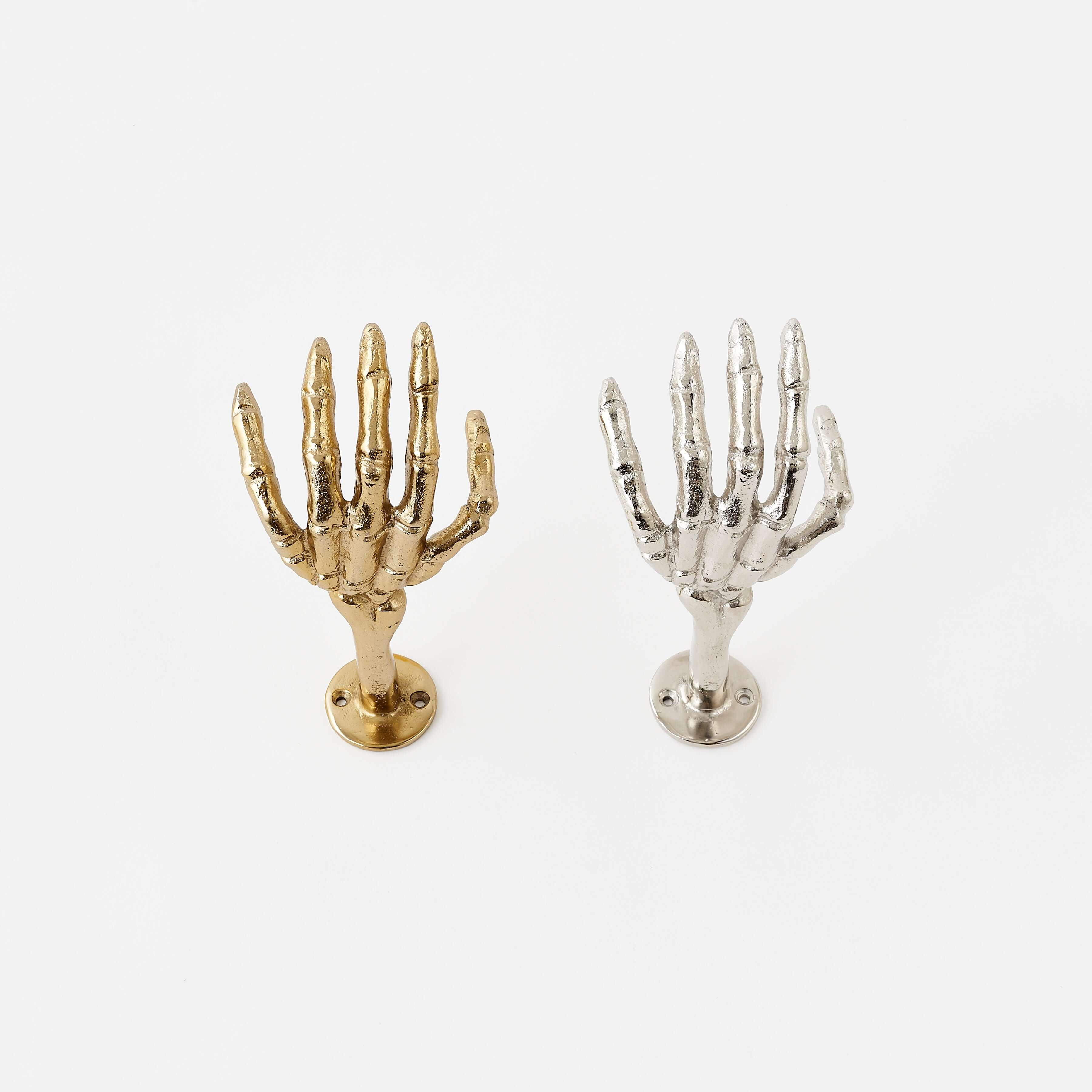 Gold and silver skeleton hand wall hooks on a white background