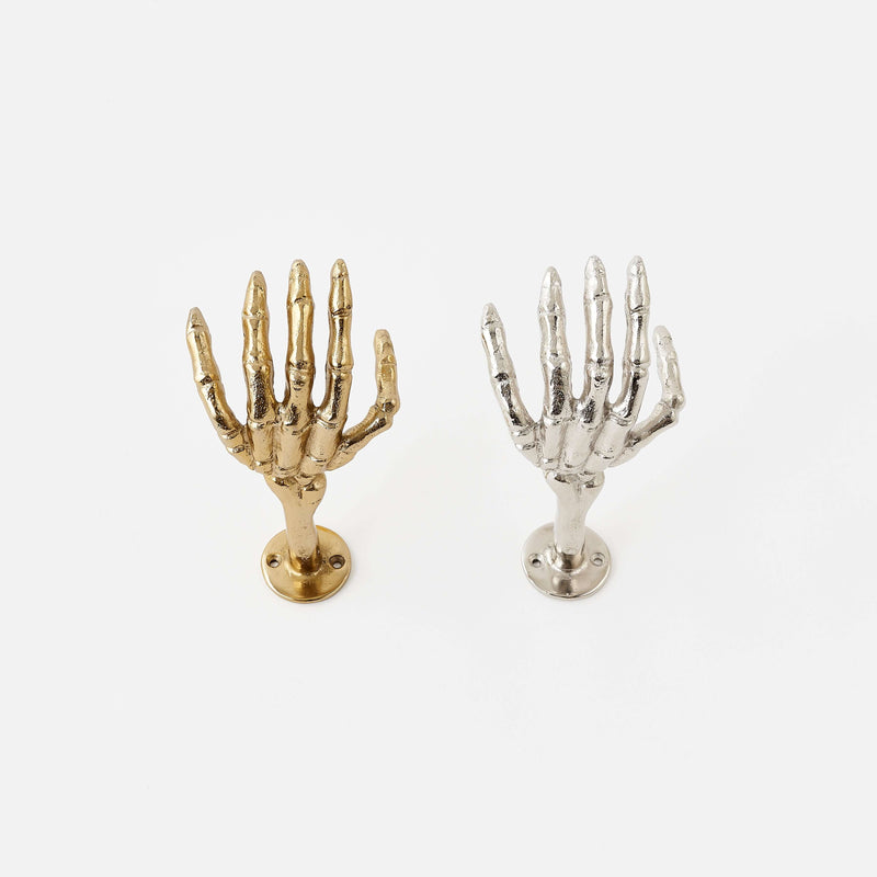 Gold and silver skeleton hand wall hooks on a white background