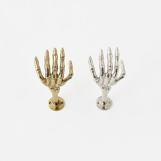 Gold and silver skeleton hand wall hooks on a white background