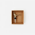 Brass pheasant-shaped bottle stopper in a cardboard box on a white background