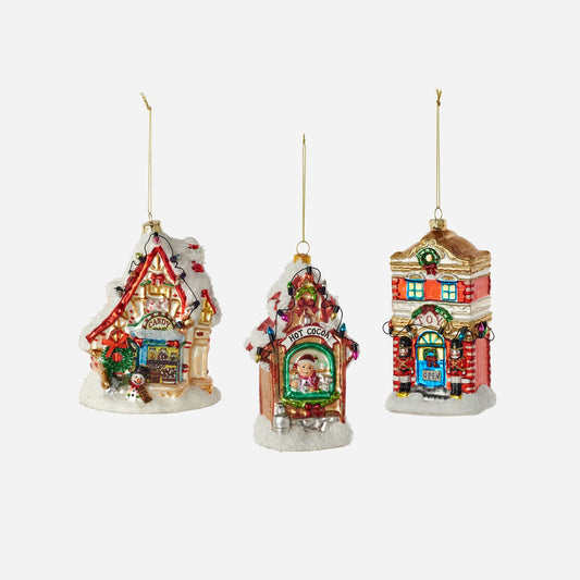 Three colorful Christmas-themed house ornaments on a white background