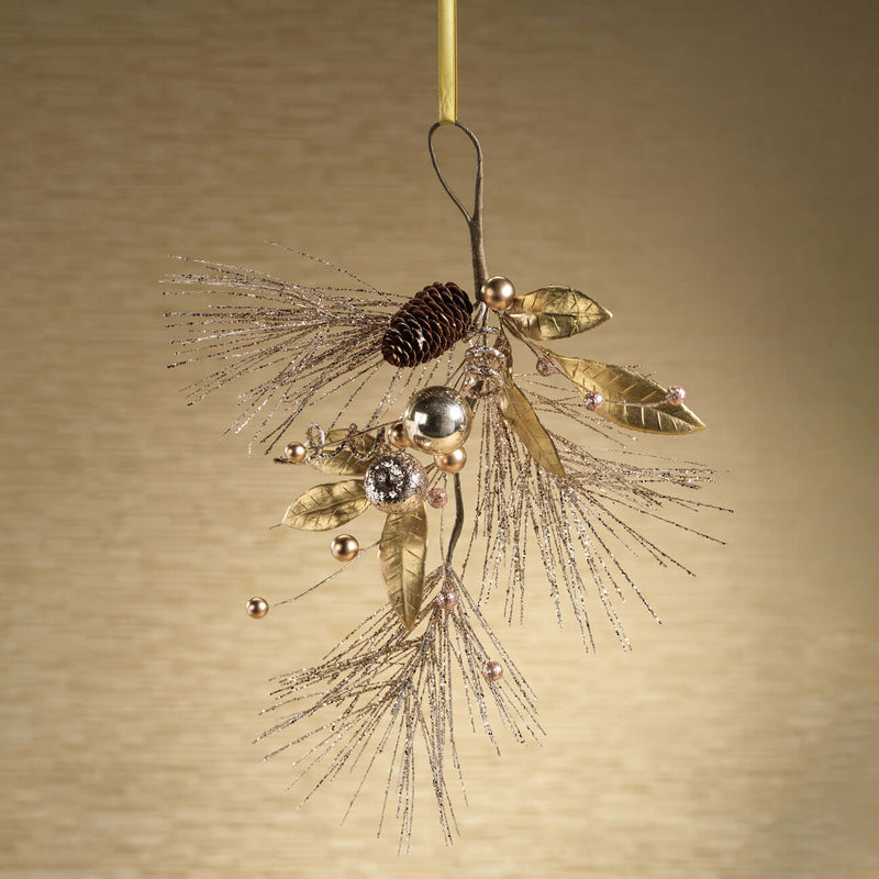 Decorative ornament with gold leaves, pinecones, and beads on a beige background