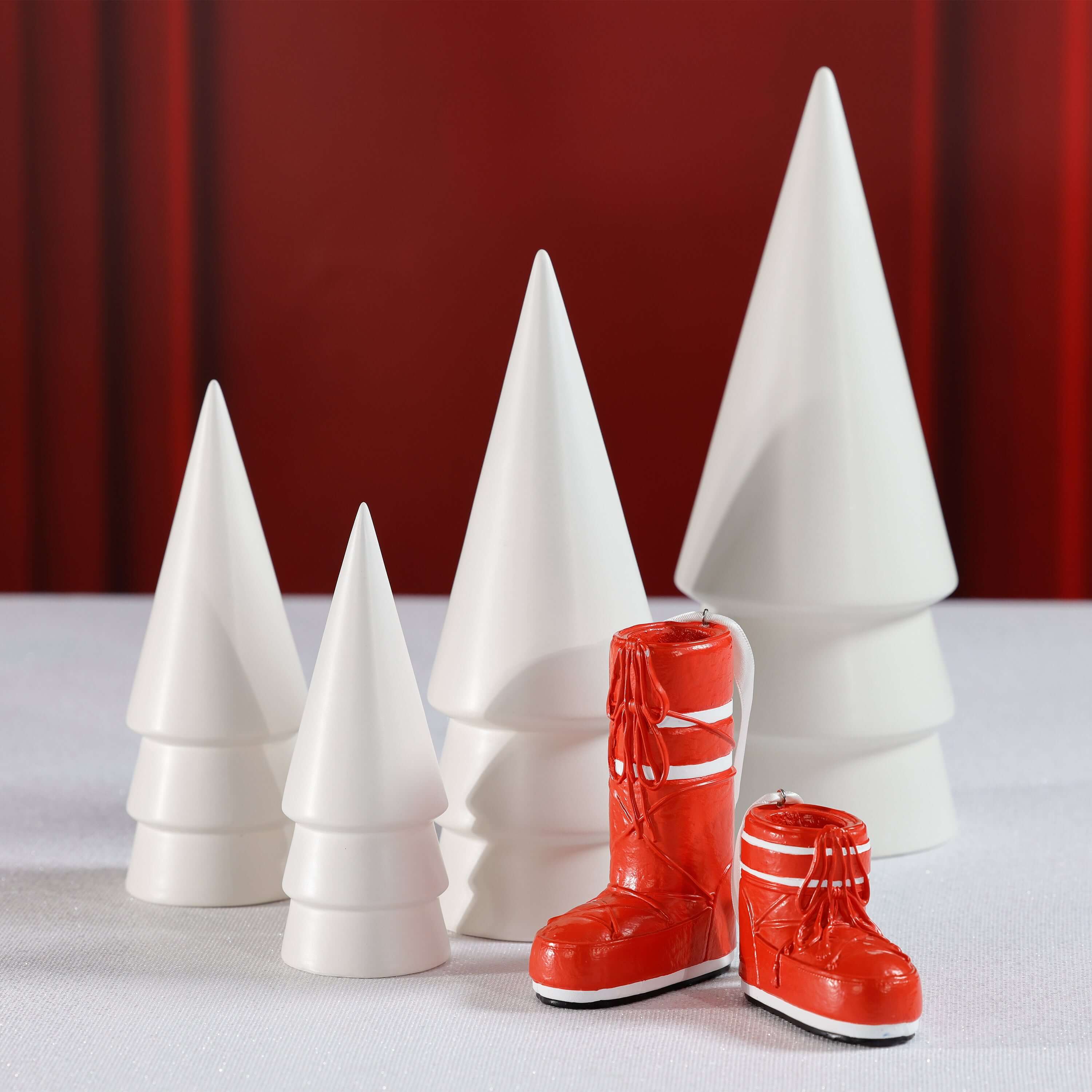 Après Ski Boots, Set of 6 Assorted decorative red ski boot ornaments next to white Christmas trees.