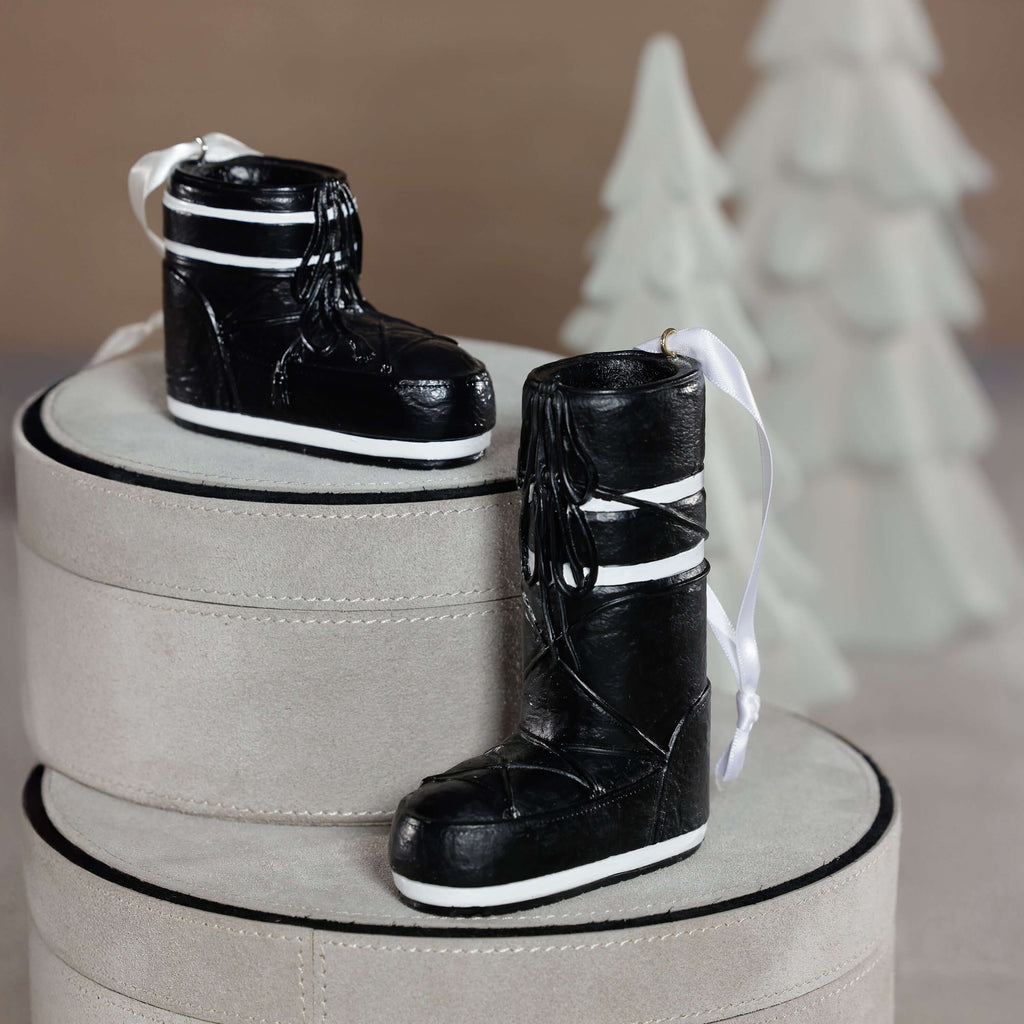 Après Ski Boots, Set of 6 Assorted black ornament displayed on grey boxes with decorative trees in the background.