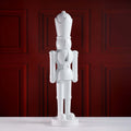 White nutcracker figurine against a red paneled wall