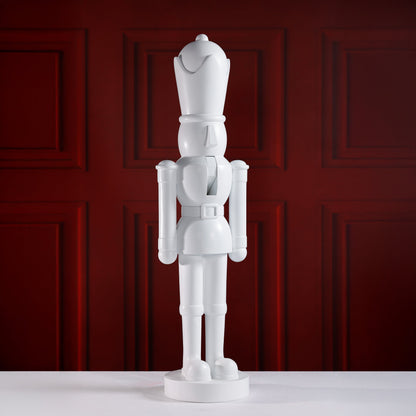 White nutcracker figurine against a red paneled wall