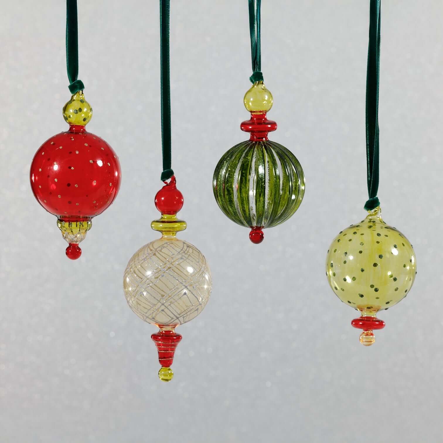 Set of colorful glass ornaments with green, red, and yellow accents on a light gray background.