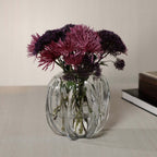 Liège Blown Glass Vase with purple flowers on a table, showcasing its sculptural design and clear glass finish.
