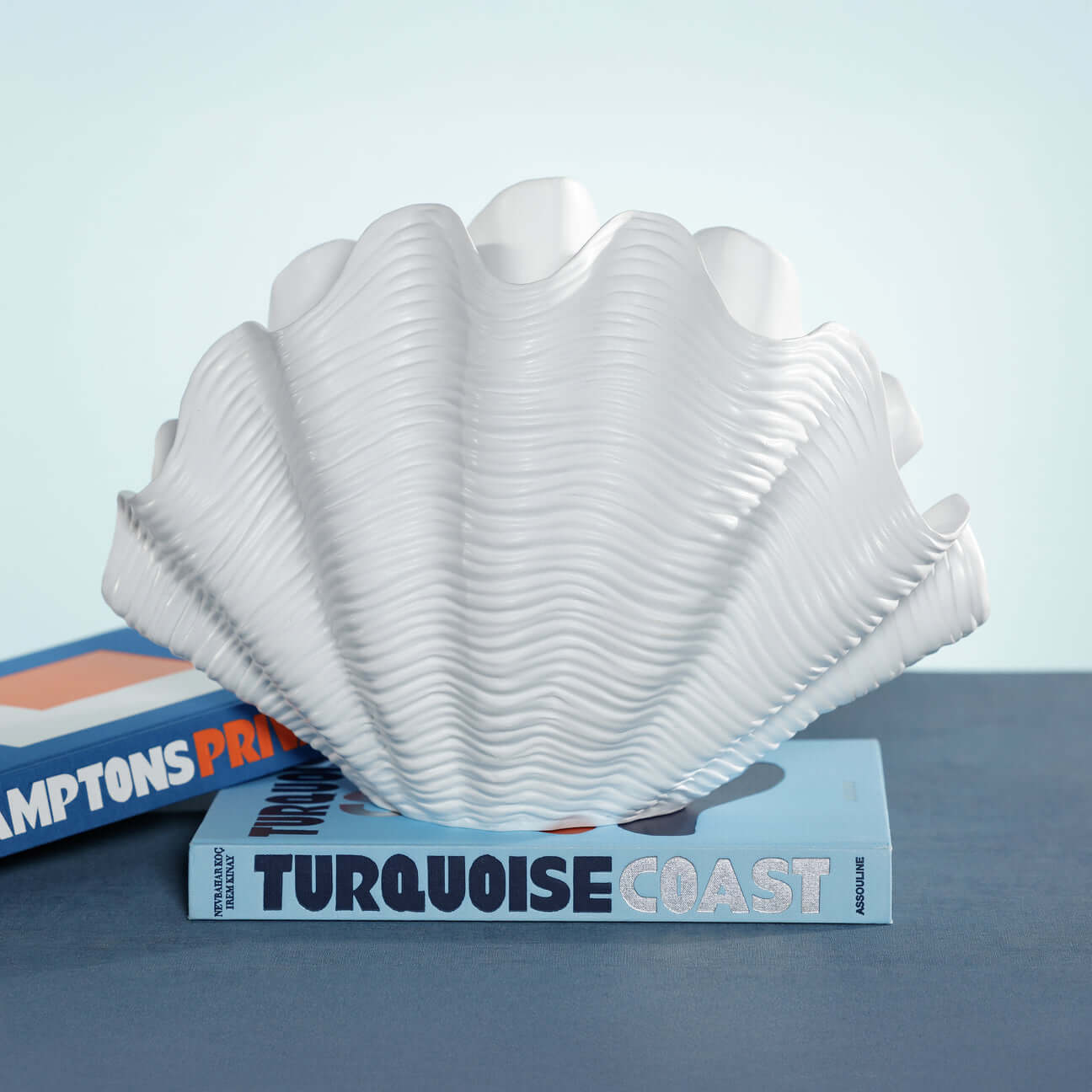 Belize Resin Decorative Shell Vase displayed on books with a white glossy finish and undulating ridges.