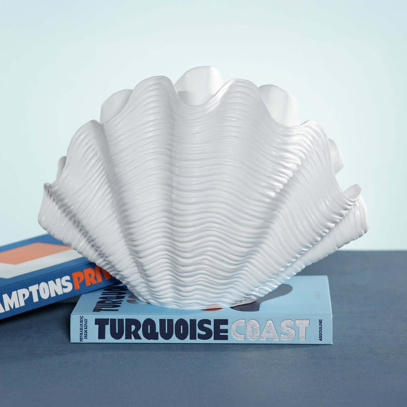 Belize Resin Decorative Shell Vase displayed on books with a white glossy finish and undulating ridges.