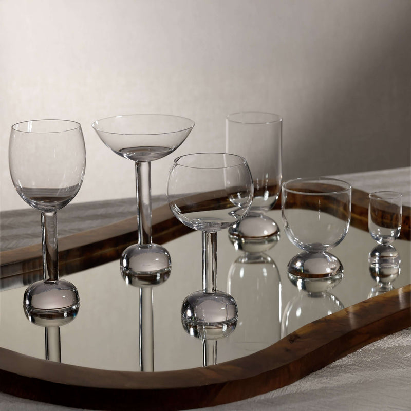 Elegant Madrid Glassware Collection displayed on a mirror tray, featuring sculptural glass designs with solid sphere bases.
