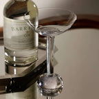 Madrid Glassware Collection elegant glass on a reflective surface next to a gin bottle.