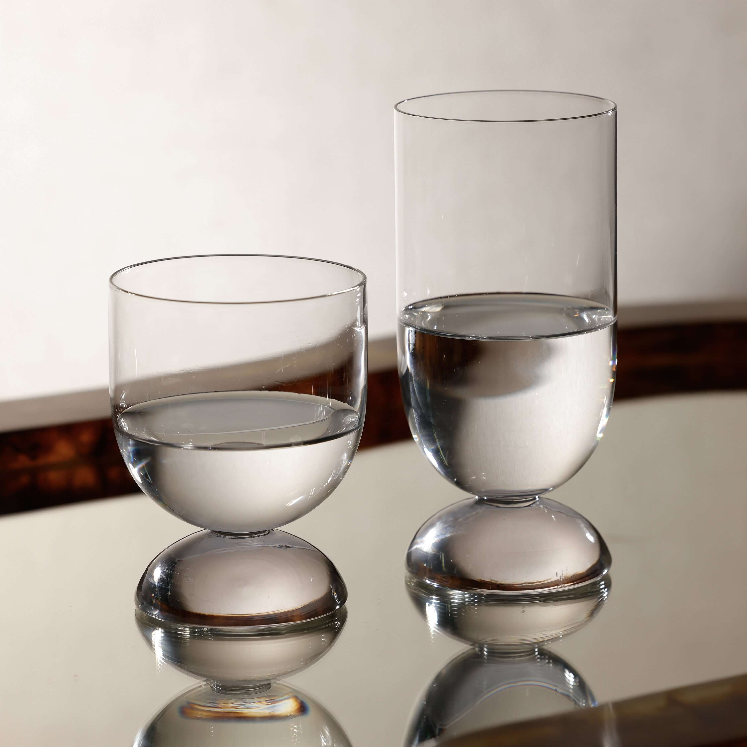 Madrid Glassware Collection featuring sculptural glasses with a solid sphere base on a reflective surface.