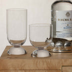 Madrid Glassware Collection displayed with two elegant glasses and a bottle of tequila on a wooden surface.