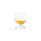 Madrid Glassware Collection: elegant glass with a solid sphere base, showcasing a drink in a sculptural design.