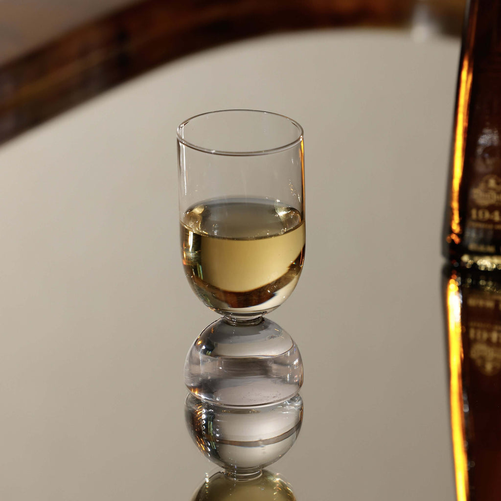 Elegant glass from the Madrid Glassware Collection reflecting on a mirror surface with a soft drink inside.