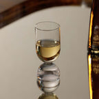Elegant glass from the Madrid Glassware Collection reflecting on a mirror surface with a soft drink inside.