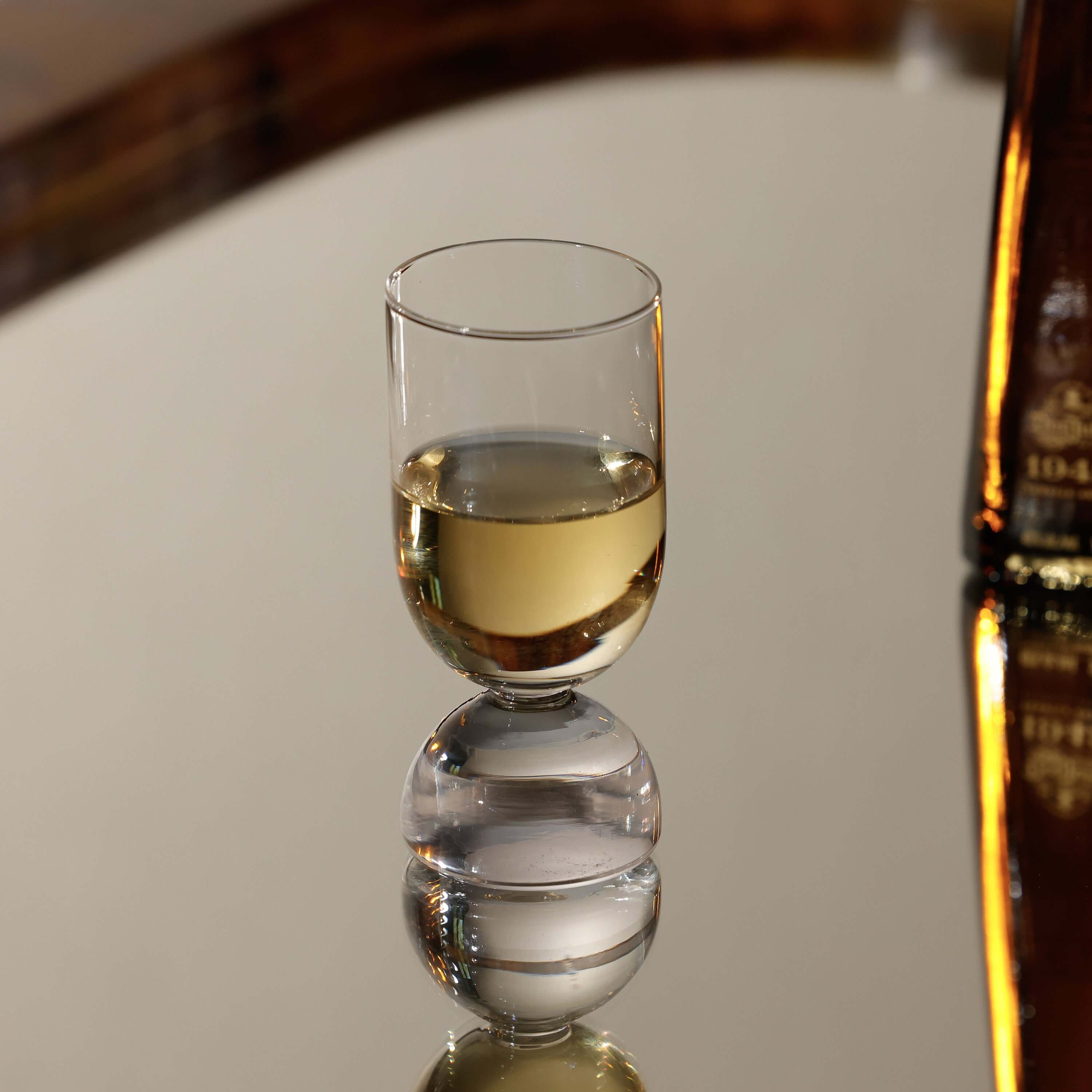 Elegant glass from the Madrid Glassware Collection reflecting on a mirror surface with a soft drink inside.