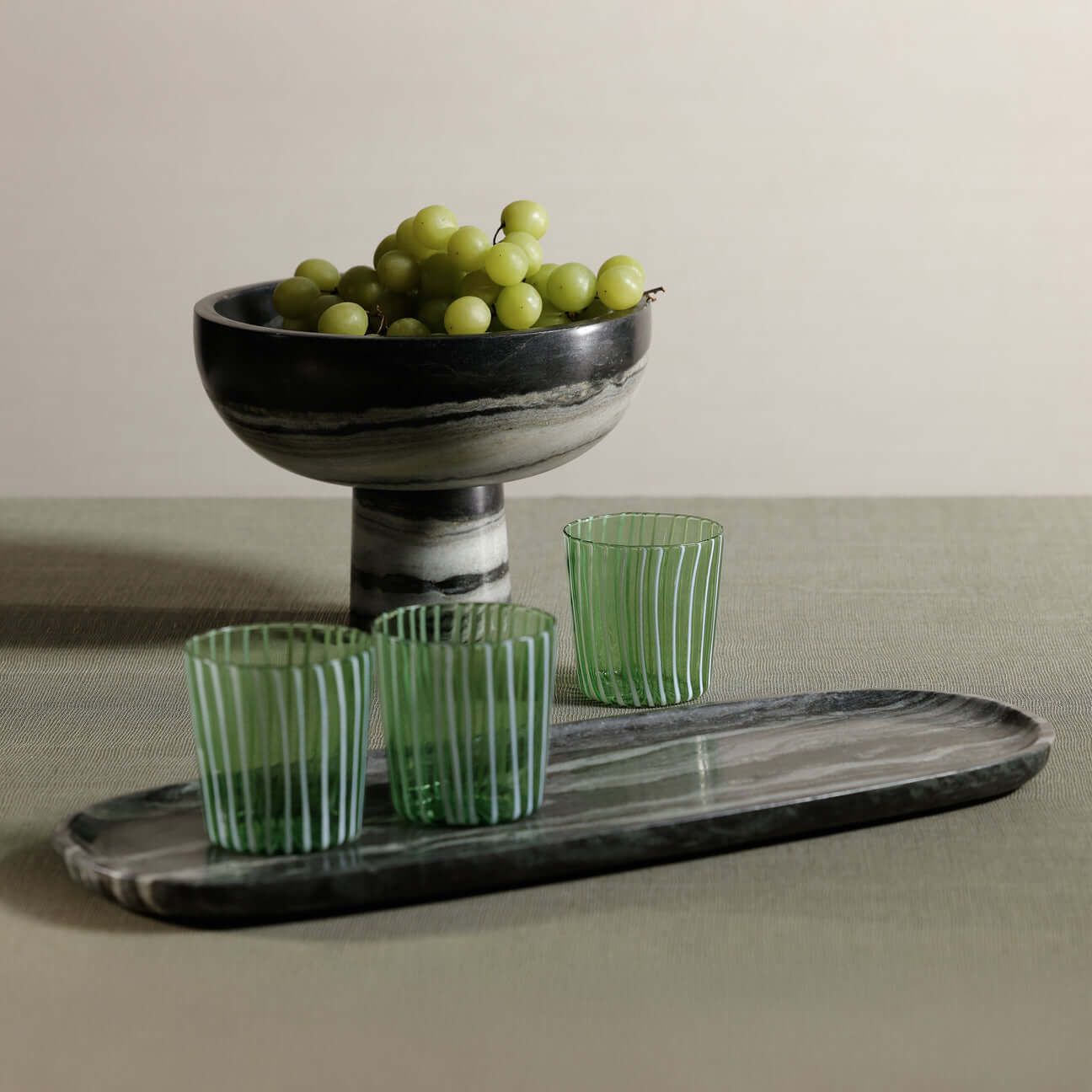 Marina White Stripe Glass Tumbler (Set of 6) displayed with green grapes and a black-striped bowl.