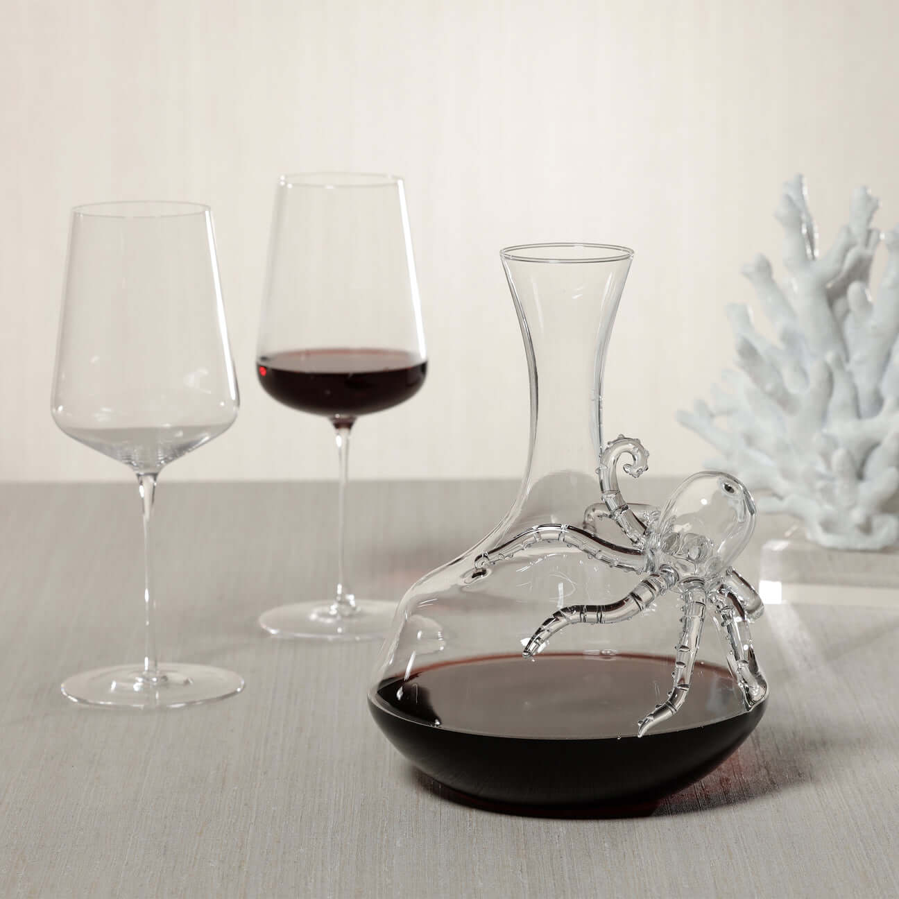 Octopus Wine Decanter with two glasses of red wine on a table, combining elegance and coastal charm.