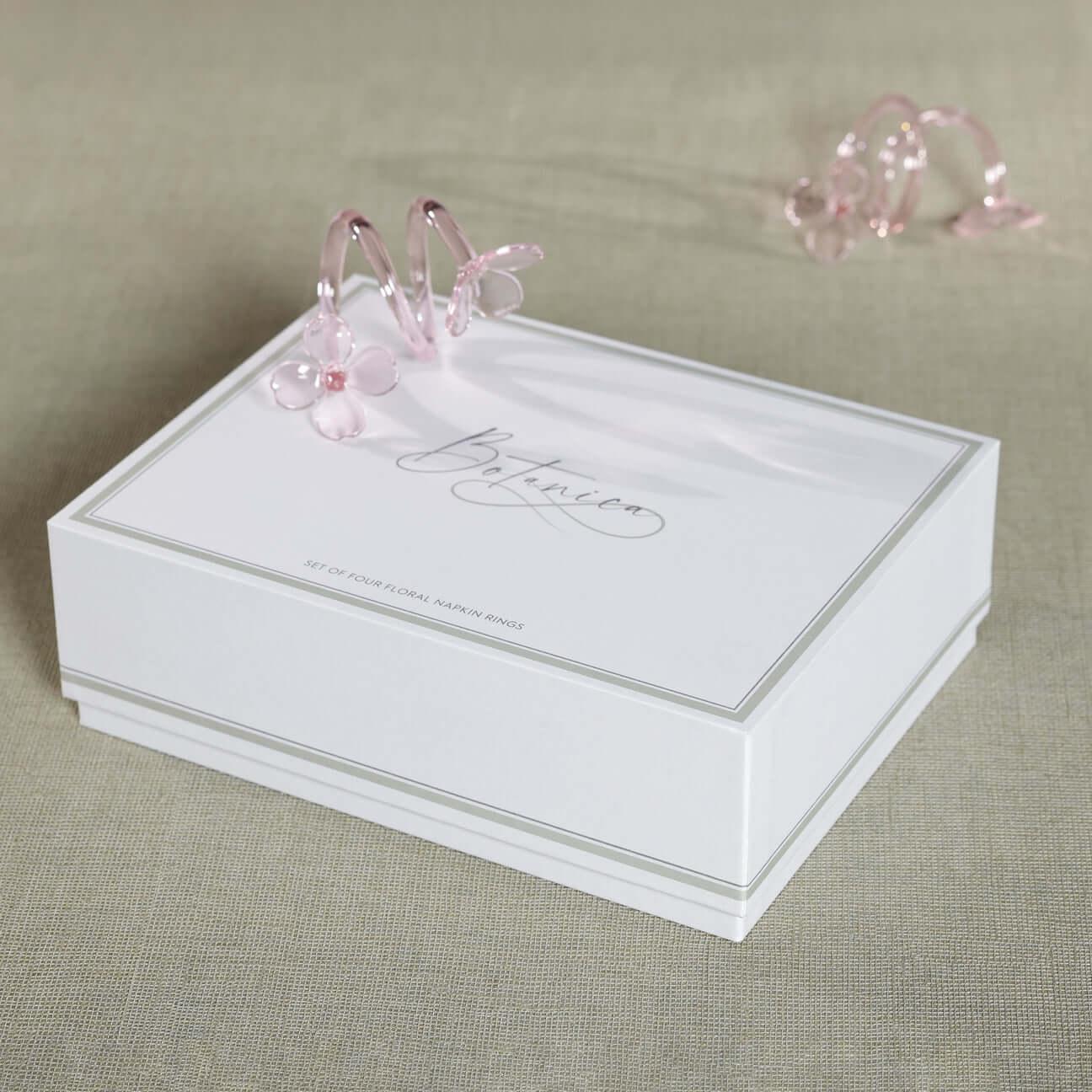 Four Botanica Glass Flower Napkin Rings - Boxed (Set of 4) showcased in elegant packaging with pink glass details.