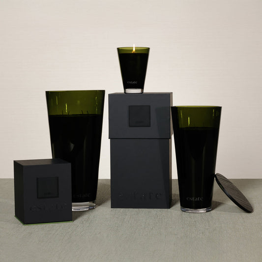 Set of black and green glass containers on a gray surface with a neutral background