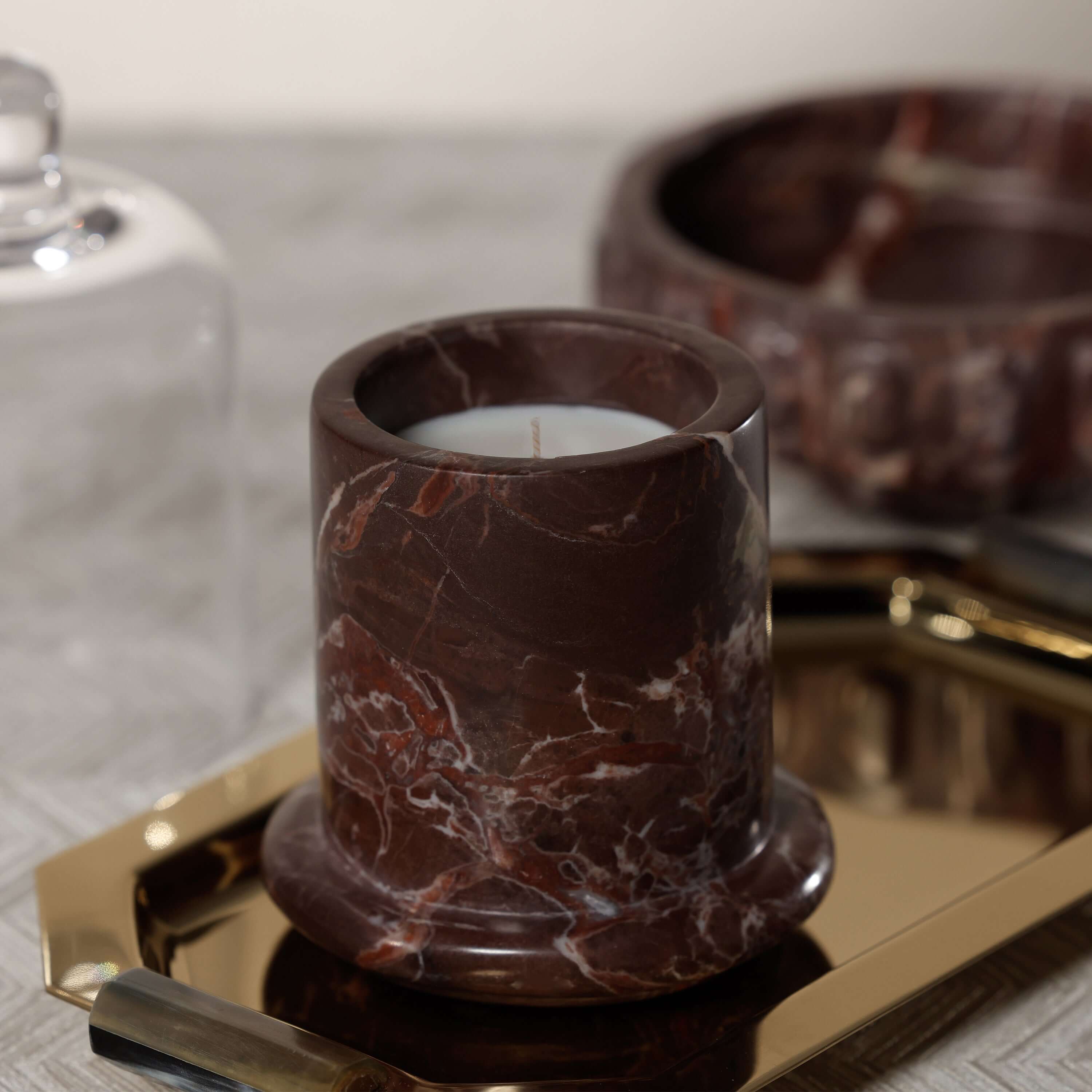 Marbella Scented Candle Jar with Cloche displayed on a gold tray, showcasing its unique marble design.