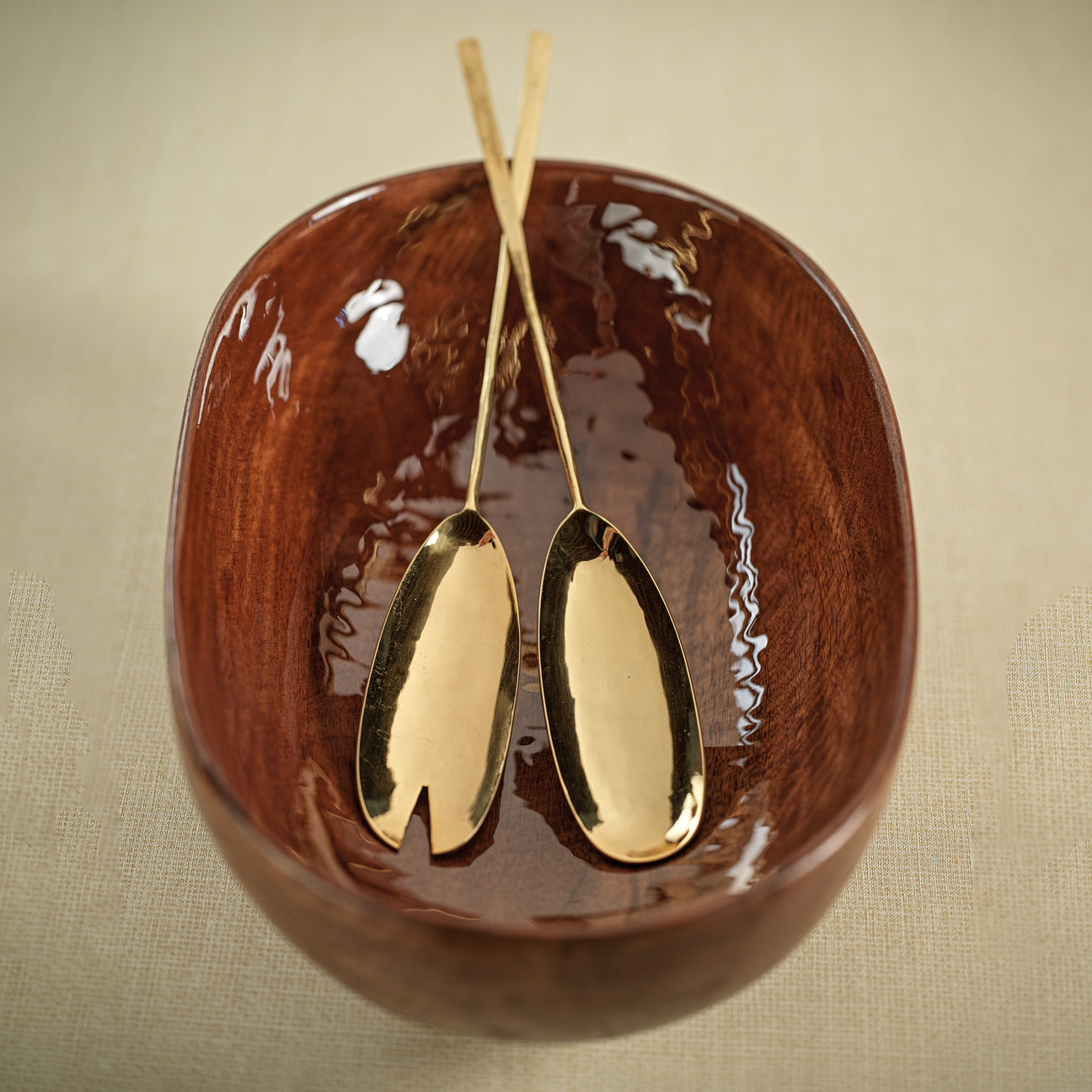 Gold serving spoons on a brown ceramic dish with a beige background