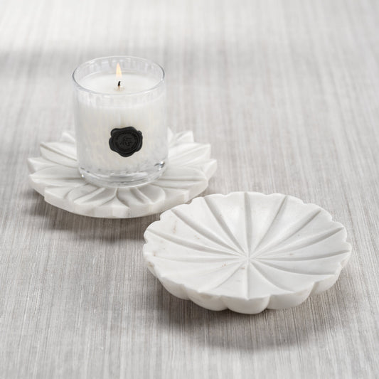 White decorative candle holder with a small candle on a light gray surface