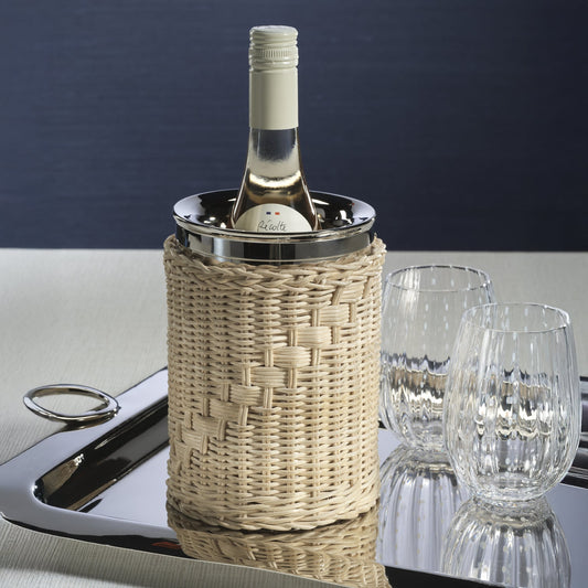 The Palmier Wine Cooler with handwoven rattan exterior and polished metal interior, holding a bottle of white wine on a tray beside glasses.