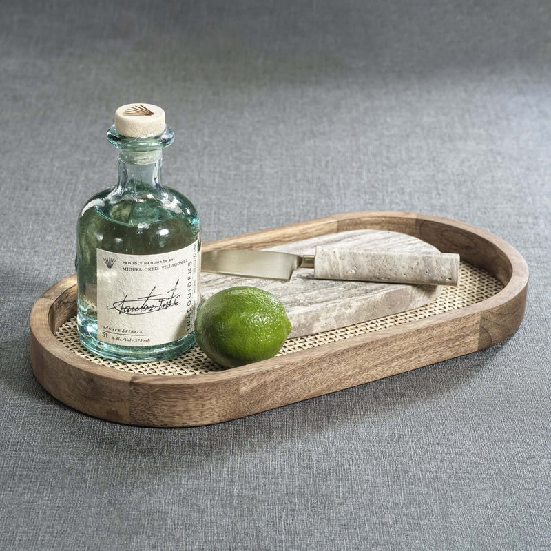 The Marais Oval Tray styled with a bottle, lime, and cheese knife on a textured background.