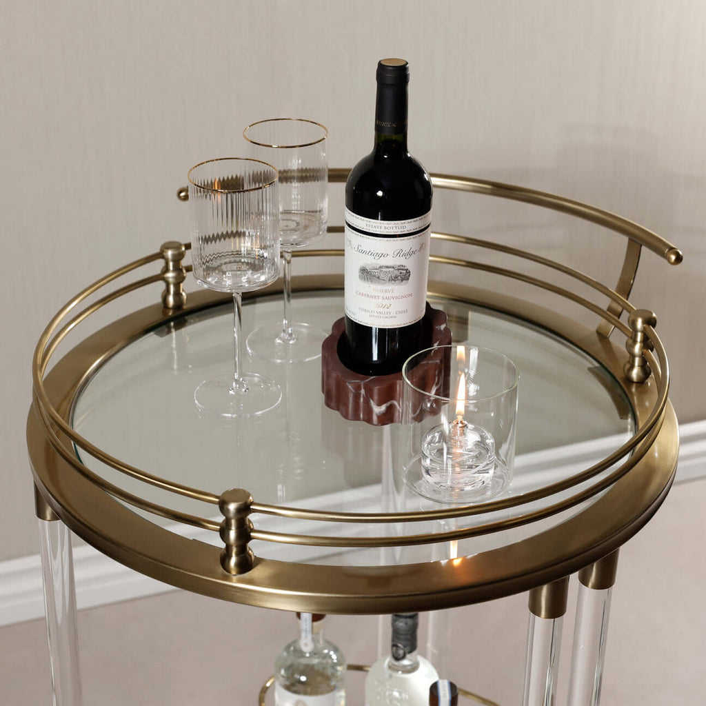 Opus Round Bar Cart / Trolley with wine bottles and glasses on a round mirrored top.